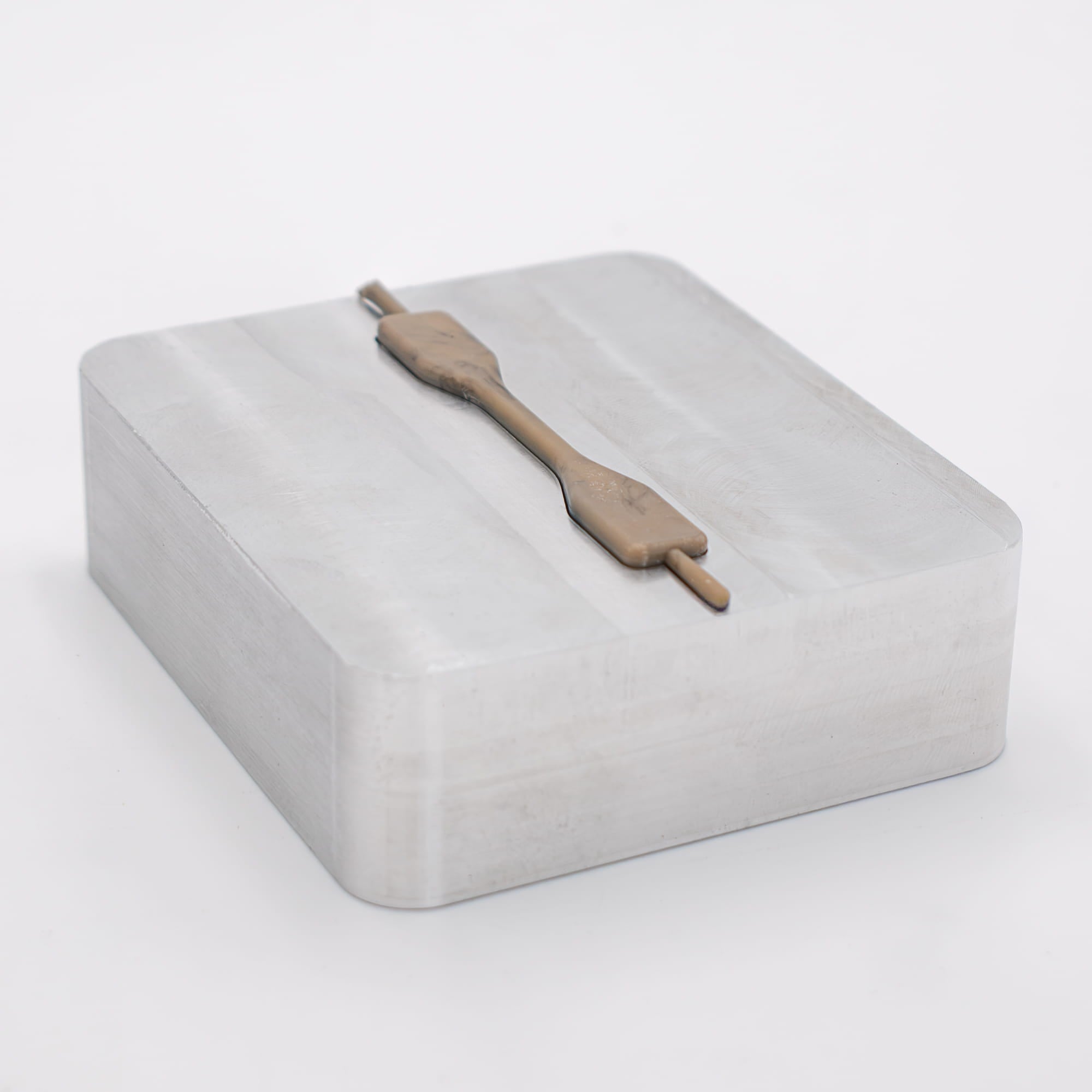 Dogbone PEEK plastic sample part on an aluminum mold made by Action BOX.